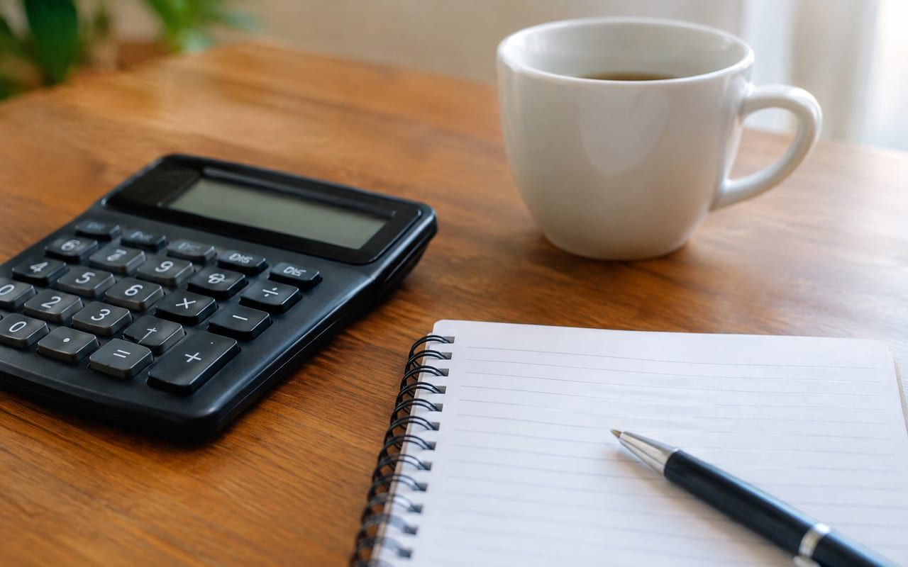Calculadora, caneta e bloco de anotações para conferir a média dos salários de contribuição