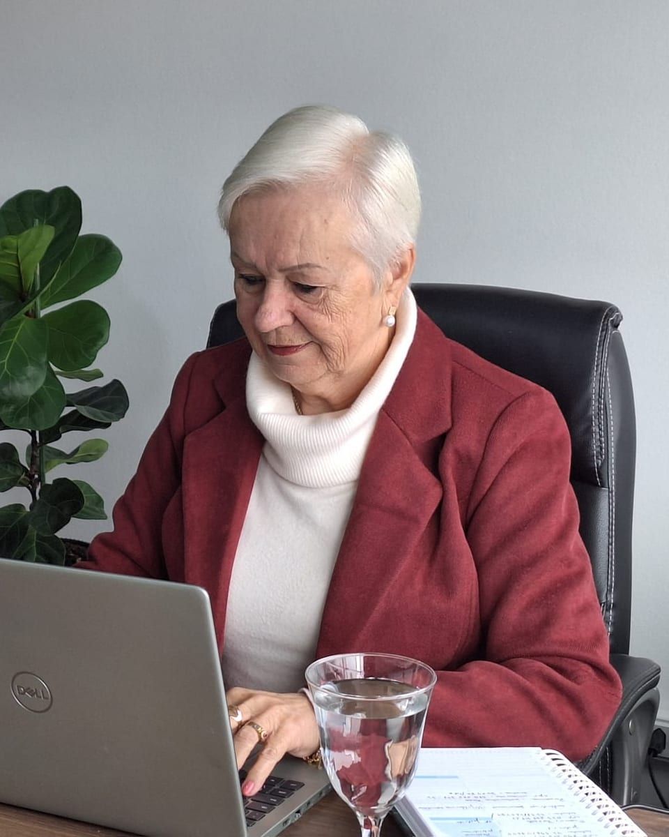 Dra. Soeli Konell ao notebook em sua mesa, com um caderno de anotações ao lado